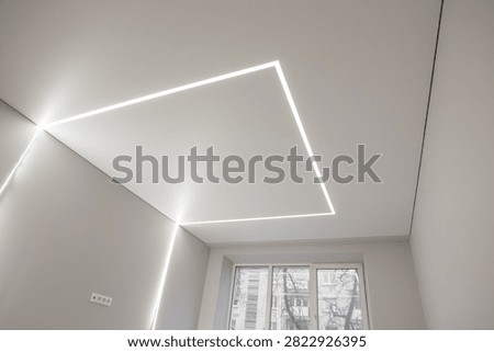 A modern matte stretch ceiling with rectangular light lines in an interior.
