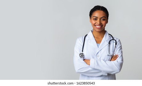 Modern Medical Education Concept. Portrait Of Smiling Black Female Doctor In White Coat Posing With Folded Arms Over Light Background, Panorama