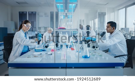 Modern Medical Research Laboratory: Diverse Team of Scientists Working with Pipette, Analysing Biochemicals Samples, Talking. Scientific Lab for Medicine, Microbiology Development. Advanced Equipment