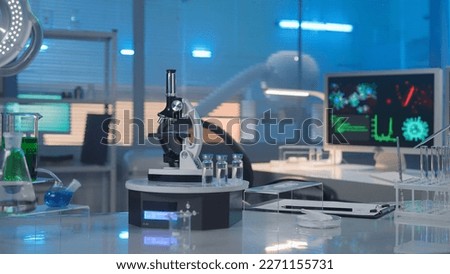 Modern medical research laboratory. Empty workplace of a scientist or researcher with computers, microscope, test tubes, flasks and magnifying lamp. Biochemical laboratory in the blue light.