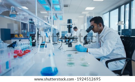 Modern Medical Research Laboratory: Male Scientist Working with Microscope, Analysing Biochemicals Samples. Advanced Scientific Lab for Medicine, Microbiology Development.