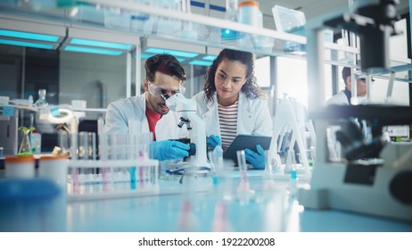 Modern Medical Research Laboratory: Portrait of Latin and Black Young Scientists Using Microscope, Digital Tablet, Doing Sample Analysis, Talking. Diverse Team of Specialists work in Advanced Lab