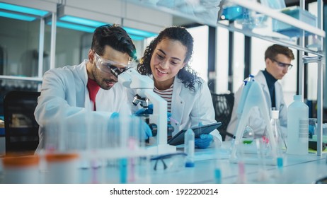 Modern Medical Research Laboratory: Portrait of Latin and Black Young Scientists Using Microscope, Digital Tablet, Doing Sample Analysis, Talking. Diverse Team of Specialists work in Advanced Lab - Powered by Shutterstock