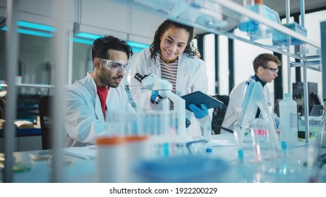 Modern Medical Research Laboratory: Portrait Of Latin And Black Young Scientists Using Microscope, Digital Tablet, Doing Sample Analysis, Talking. Diverse Team Of Specialists Work In Advanced Lab