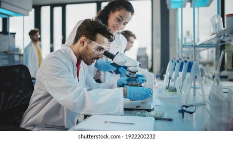 Modern Medical Research Laboratory: Portrait of Latin and Black Young Scientists Using Microscope, Digital Tablet, Doing Sample Analysis, Talking. Diverse Team of Specialists work in Advanced Lab - Powered by Shutterstock