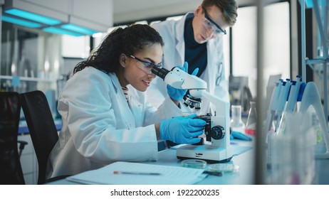 Modern Medical Research Laboratory: Portrait of Two Young Scientists Microscope, Digital Tablet, Doing Sample Analysis, Talking. Diverse Team of Multi-Ethnic Specialists work in Advanced Lab - Powered by Shutterstock