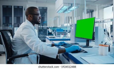 Modern Medical Research Laboratory: Portrait Of Male Scientist Working On Computer Showing Green Chroma Key Screen. Scientific Lab, Medicine Development Facility With Advanced Equipment, Biotechnology