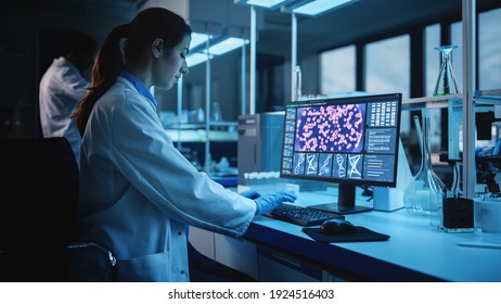 Modern Medical Research Laboratory: Portrait Of Female Scientist Working On Computer, Analysing Biochemicals, Talking. Advanced Scientific Lab For Medicine, Biotechnology Development. Dark Evening