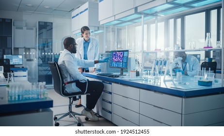 Modern Medical Research Laboratory: Two Scientists Use Computer With Screen Showing DNA Gene Analysis, Specialists Discuss Innovative Technology. Advanced Scientific Lab For Medicine, Biotechnology