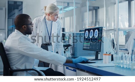 Modern Medical Research Laboratory: Two Scientists Use Computer with Screen Showing MRI Brain Scans, Specialists Discuss Innovative Technology. Advanced Scientific Lab for Medicine Foto stock © 