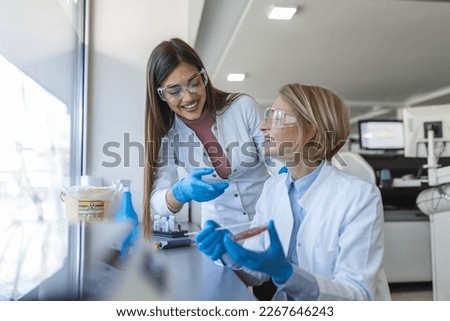 Modern Medical Research Laboratory: Two Scientists Working Together Analysing Chemicals in Laboratory, Discussing Problem. Advanced Scientific Lab for Medicine, Biotechnology, Molecular Biology