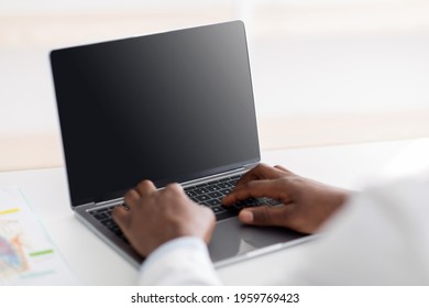 Modern Medicine At Covid-19. African American Male Doctor Using Laptop Computer With Black Empty Screen, Sitting At Workplace In Office, Closeup, Crop. Mockup For Ad