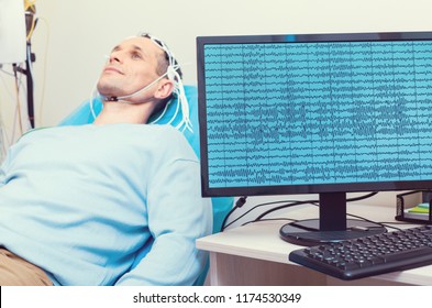 Modern medicine. Selective focus on a computer recording brain waves of a mature gentleman getting his brain analyzed by an electroencephalography machine.