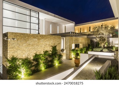 Modern Mediterranean Courtyard With Stone Walls and Nighttime Lighting. Magnificent night view of the illuminated villa with landscaping. - Powered by Shutterstock