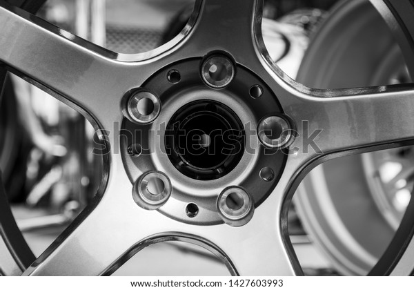 Modern metal alloy\
wheel for cars. Showcase with rims. Closeup side and front view.\
Black and white photo