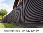 Modern metal fence for fencing the yard area. Horizontal sections of the fence made of metal