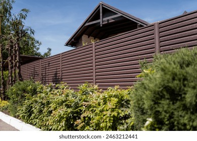 Modern metal fence for fencing the yard area. Horizontal sections of the fence made of metal