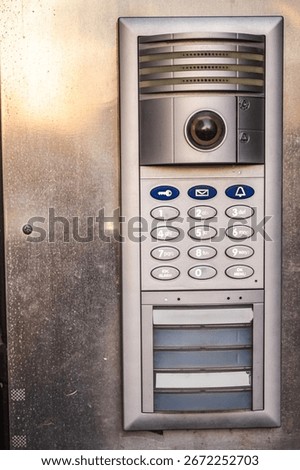 Modern metal intercom with keypad and camera mounted on building entrance. High quality photo