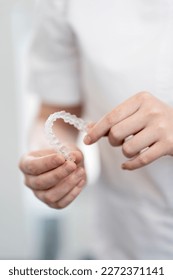 Modern methods of teeth alignment. Closeup, the doctor is holding an aligner to straighten the teeth.