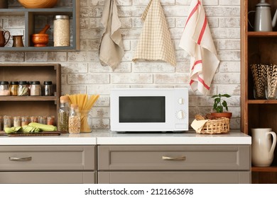 Modern microwave oven on counter near light brick wall in stylish kitchen - Shutterstock ID 2121663698