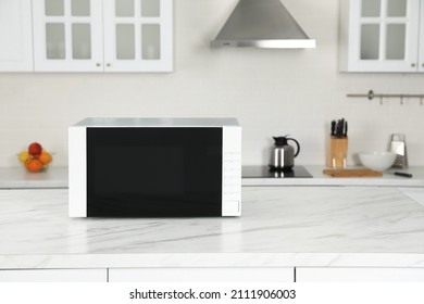 Modern microwave oven on white table in kitchen, space for text