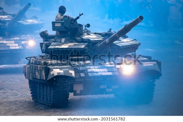 Modern\
military tank. With a serviceman behind a machine gun on the smoky\
streets of the city moves with the headlight\
on.