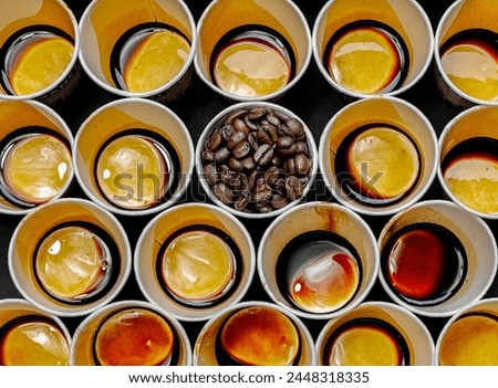 Modern minimal art creativity, standout concept.  Many used take away coffee paper cups arranging on black background with one cup filled with roast coffee beans.