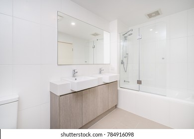 Modern Minimal Bathroom Interior With Wooden Cabinets And Glass Shower Screen.