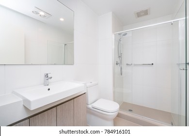 Modern Minimal Bathroom Interior With Wooden Cabinets And Glass Shower Screen.