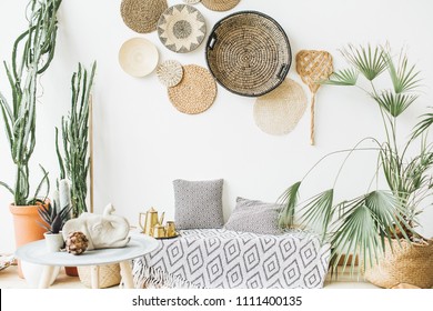 Modern minimal home interior design. Pillows, golden teapot, decorative straw plates, Scandinavian blanket, tropical palm tree, succulent and decorations. - Shutterstock ID 1111400135