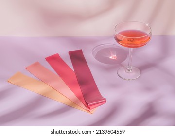 Modern minimal summer fitness concept with cocktail glass, sun shadow and elastic booty bands on pastel purple background. Trendy pink sport aesthetic.