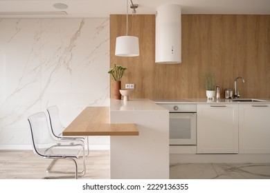 Modern and minimalist kitchen with white furniture, wooden elements and marble floor and wall - Shutterstock ID 2229136355