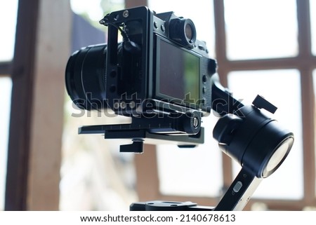 Modern mirrorless camera on 3-axis gimbal stabilizer with recording cable attached to camera and stabilizer
