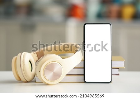 Modern mobile phone, headphones and books on table