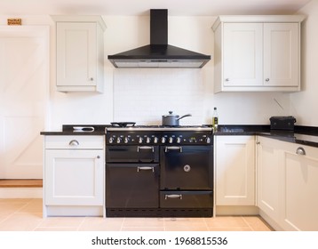 Modern modular kitchen interior in black and off white, with range cooker and chimney extractor hood. UK painted wood farmhouse kitchen design. - Shutterstock ID 1968815536