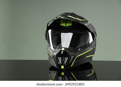 Modern motorcycle helmet with visor on mirror surface against light grey background. Space for text