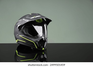 Modern motorcycle helmet with visor on mirror surface against light grey background. Space for text