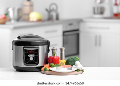 Modern multi cooker and products on table in kitchen. Space for text