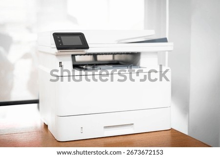 Modern multifunction printer with touchscreen interface placed on wooden desk in office. Suitable for business printing, scanning, and copying tasks in professional workplace environments.
