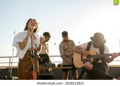 Modern music band of singer and guitarist performing at rooftop party or concert - Shutterstock ID 2018213813