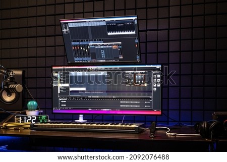 Modern music recording studio equipment. Computer screen showing user interface of digital audio workstation software with track song on a sound acoustical foam background in recording studio