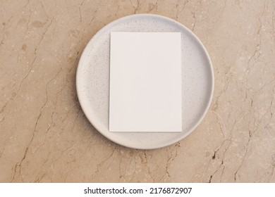 Modern Neutral Branding Stationery. Blank Greeting Card, Invitation Mockup On Dotted, Speckled Ceramic Plate. Beige Marble Stone, Table Background. Flat Lay, Top View. No People. Minimal Composition.