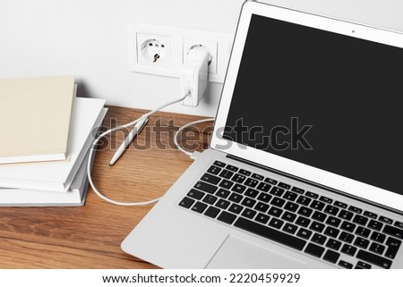Modern new laptop charging on wooden table