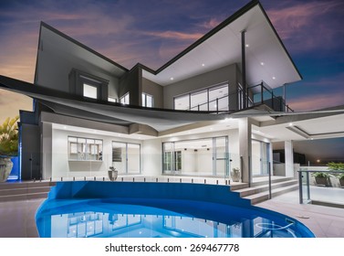 Modern New Luxurious Mansion Exterior With Swimming Pool And Colorful Sky At Dusk 