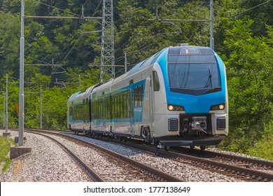 Modern and new passenger swiss made Train in white and blue color is traveling on a dual track railway line in the rural setting on a sunny hot day. - Shutterstock ID 1777138649