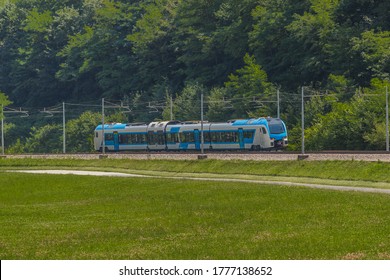 Modern and new passenger swiss made Train in white and blue color is traveling on a dual track railway line in the rural setting on a sunny hot day. - Shutterstock ID 1777138652