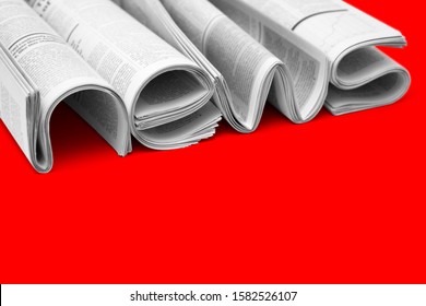 Modern newspapers are folded and composing together the word NEWS, isolated over colored background. Concept of business news, news media, print media and mass media at all. Copy space for your text