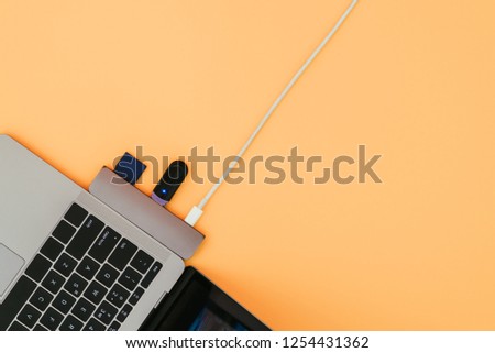Modern notebook, USB Type-C adapter with a flash and charging on orange background. Technology concept. Adapter for new standards.