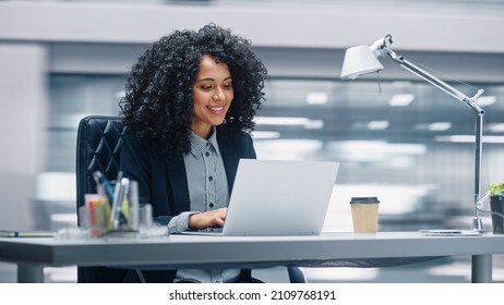 Modern Office: Black Businesswoman Sitting at Her Desk Working Laptop Computer  Smiling Successful African American Woman working and Big Data e  Commerce  Motion Blur Background