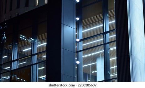 Modern office building in city at the night. View on illuminated offices of a corporate building. Blinking light in window of the multi-storey building of glass and steel. Long exposure at night